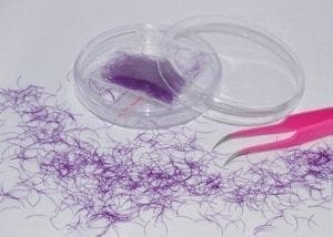A purple thread and pink scissors on top of a table.