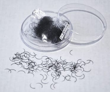 A container of hair clips and some black hair.