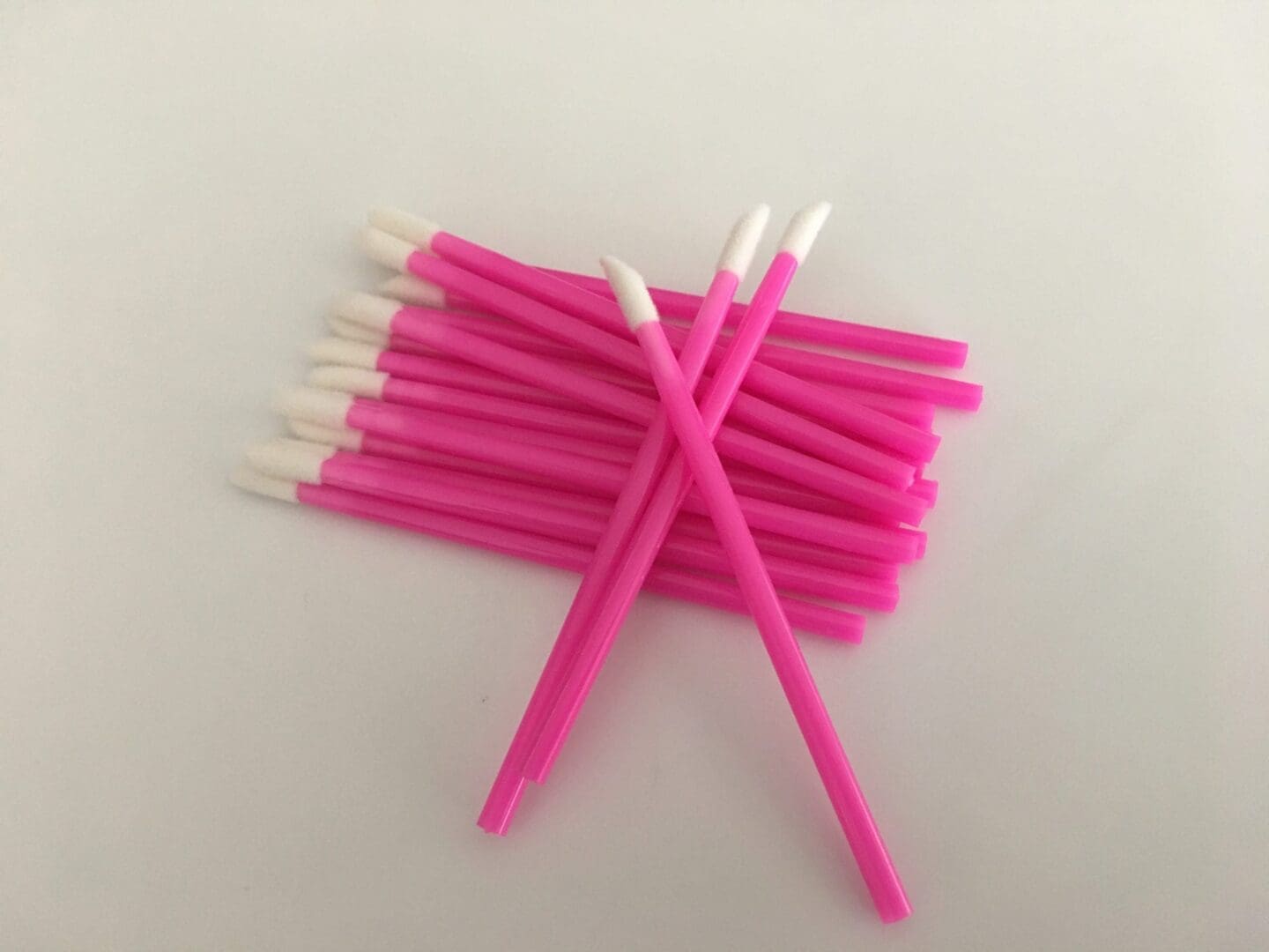A bunch of pink toothbrushes are laying on the table