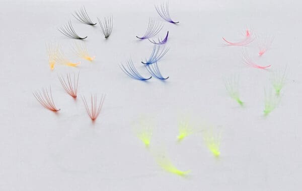 A group of different colored eyelashes on top of white paper.